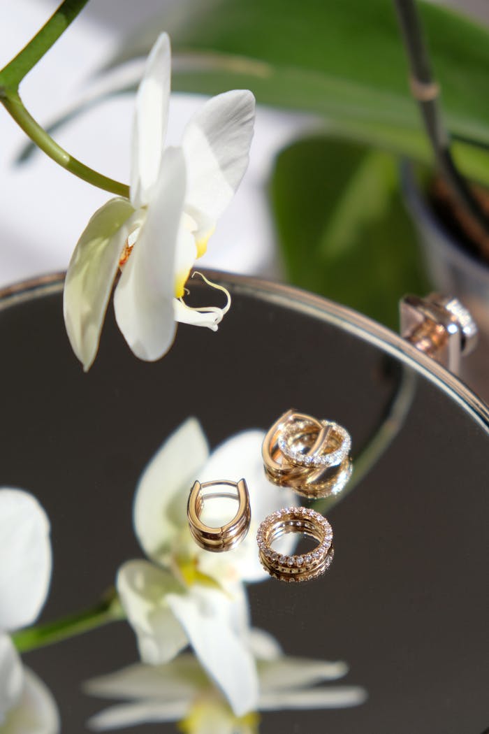 Orchid and gold jewelry elegantly displayed on a reflective surface.